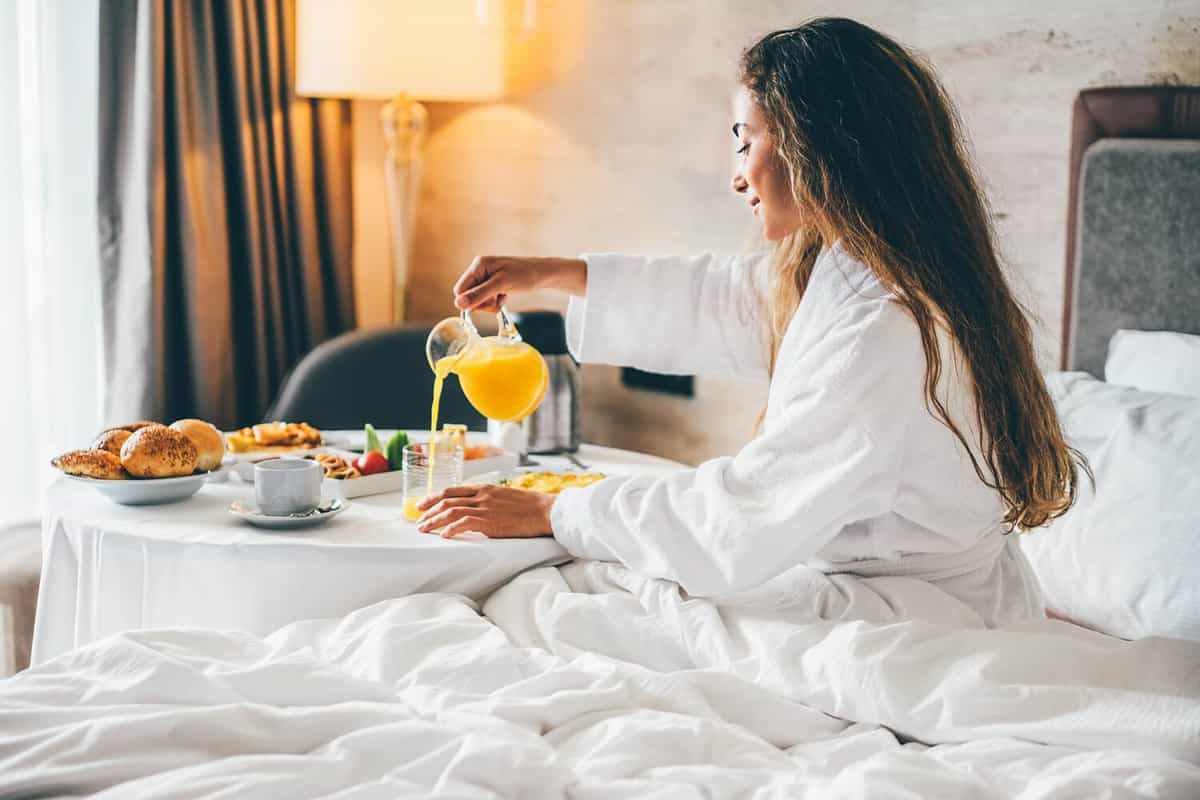 Woman eating breakfast in the hotel room. Room service breakfast in hotel room.