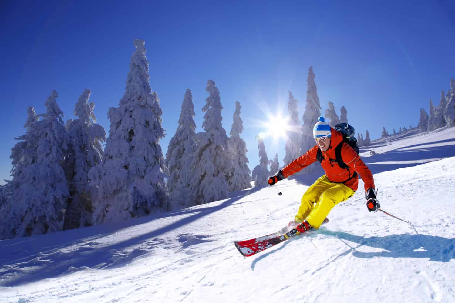 Skier skiing downhill in high mountains against sunshine