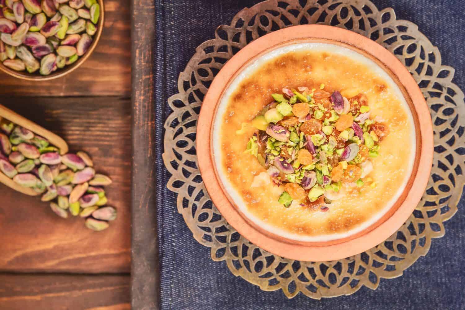 Arabic Cuisine; Traditional Egyptian dessert "Om Ali" or "Umm Ali" of soaked bread, milk and load of roasted nuts and raisins. Top view with close up.