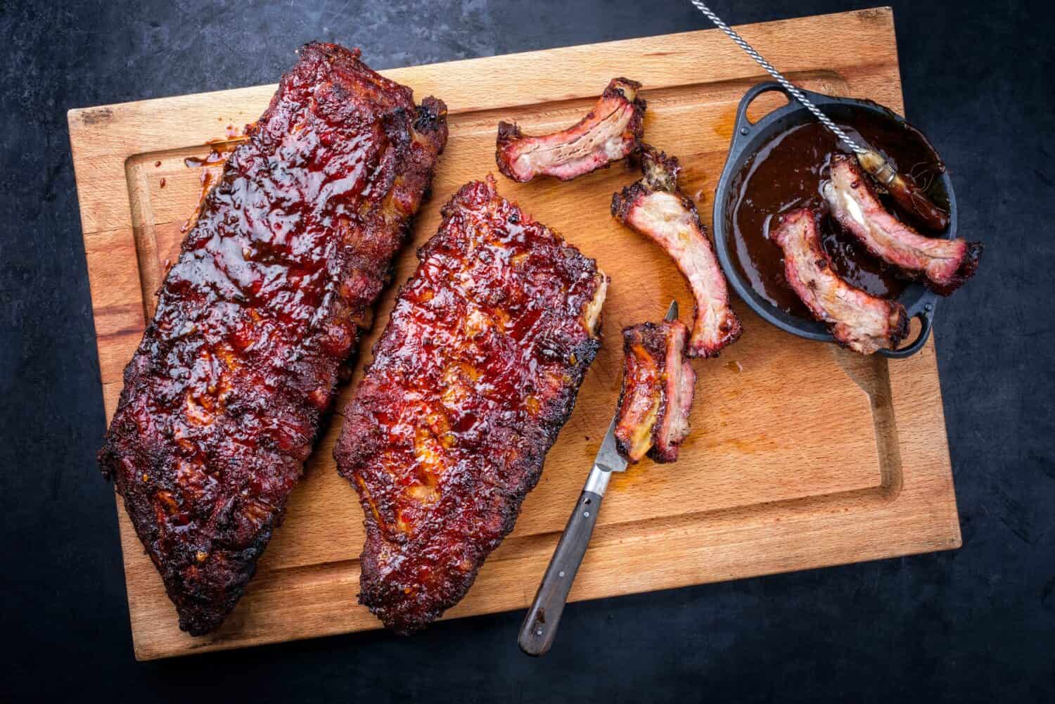 Barbecue pork spare loin ribs St Louis cut with hot honey chili marinade burnt as top view on a wooden cutting board 