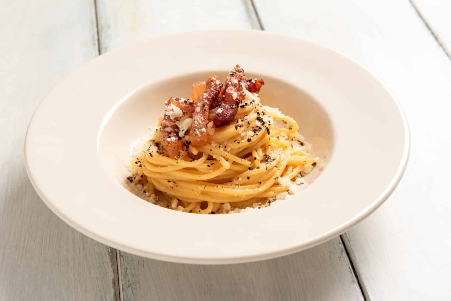 Delicious spaghetti alla carbonara, a traditional roman recipe of pasta topped with egg, pecorino and black pepper sauce, italian food 