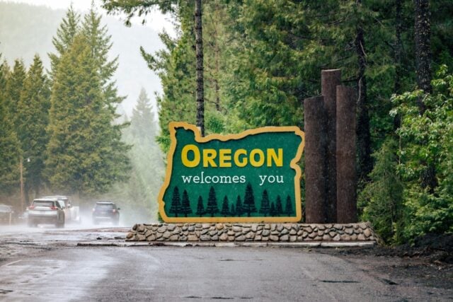 Oregon welcomes you sign at state line. US-HWY 199 Redwood Highway in rain.