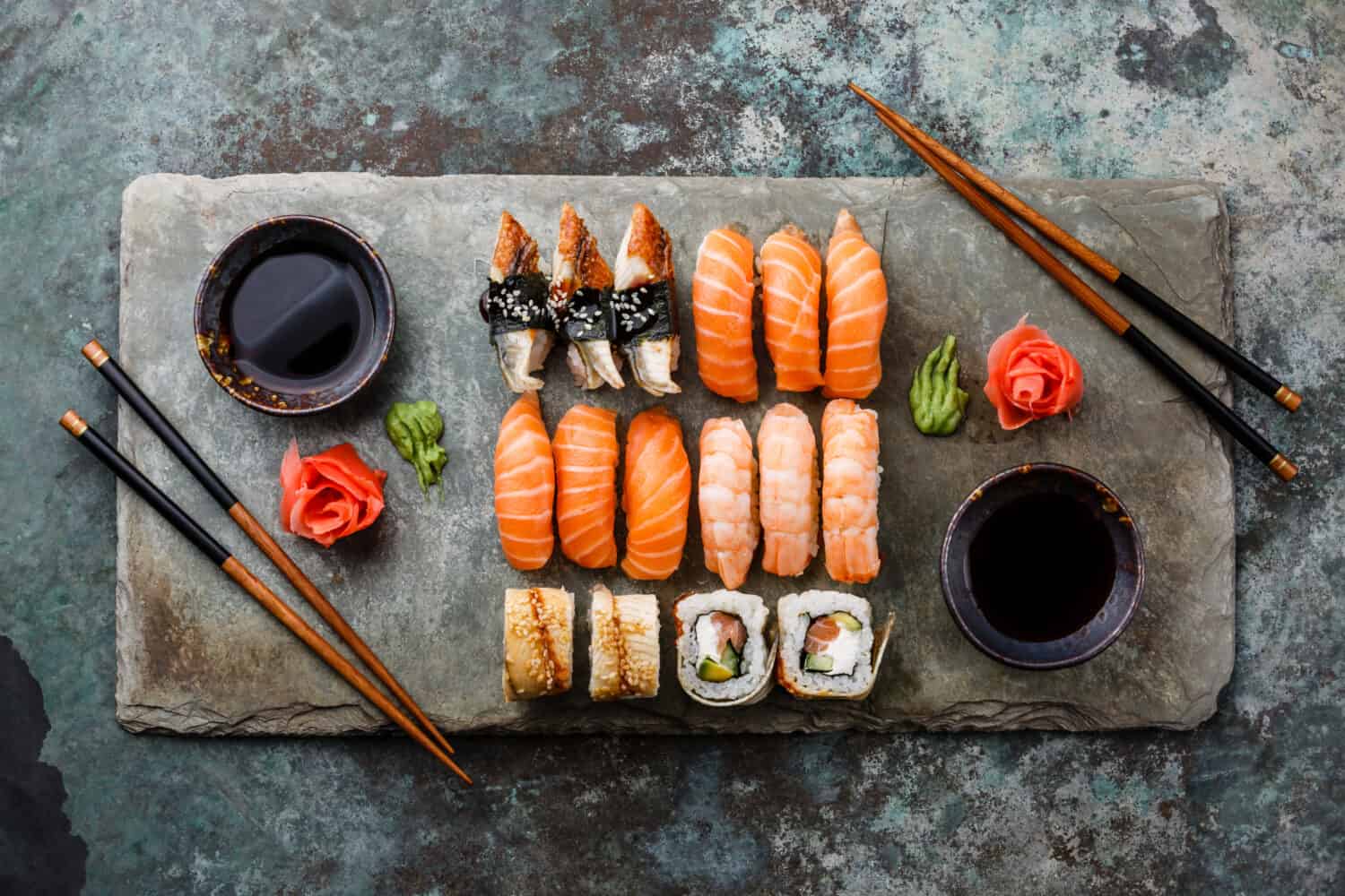 Sushi Set sashimi and sushi rolls served on stone slate