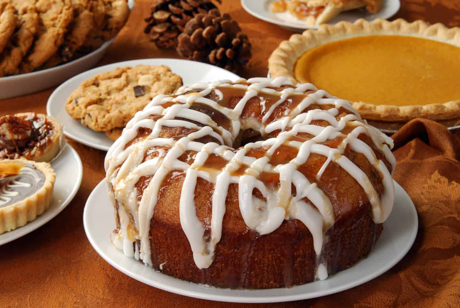 An apple bundt cake with caramel glaze and frosting and other holiday treats