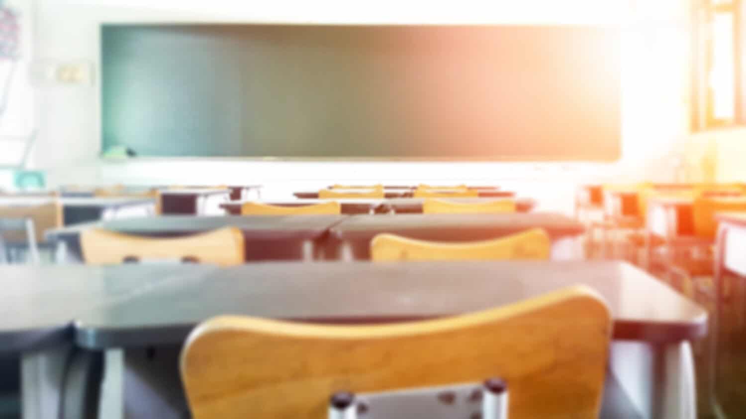 School classroom in blur background without young student; Blurry view of elementary class room no kid or teacher with chairs and tables in campus.