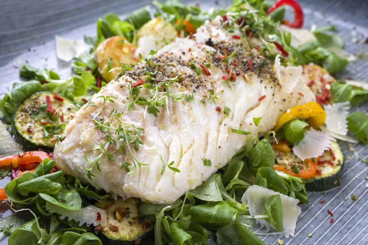 Fried cod fish fillet with lettuce and vegetable as close-up on a plate