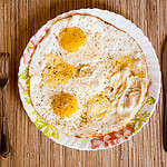 Fried eggs lie on a plate on a wooden table