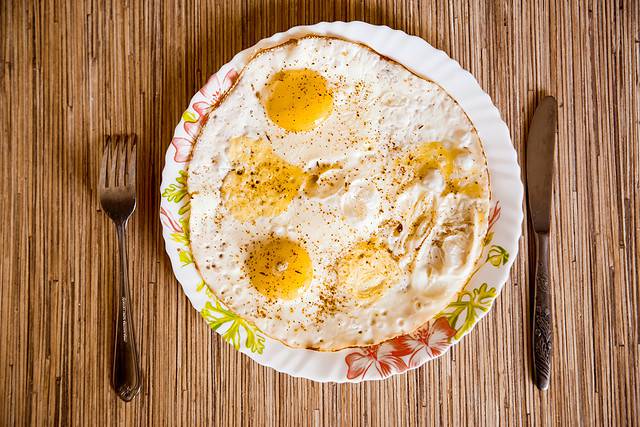 Fried eggs lie on a plate on a wooden table