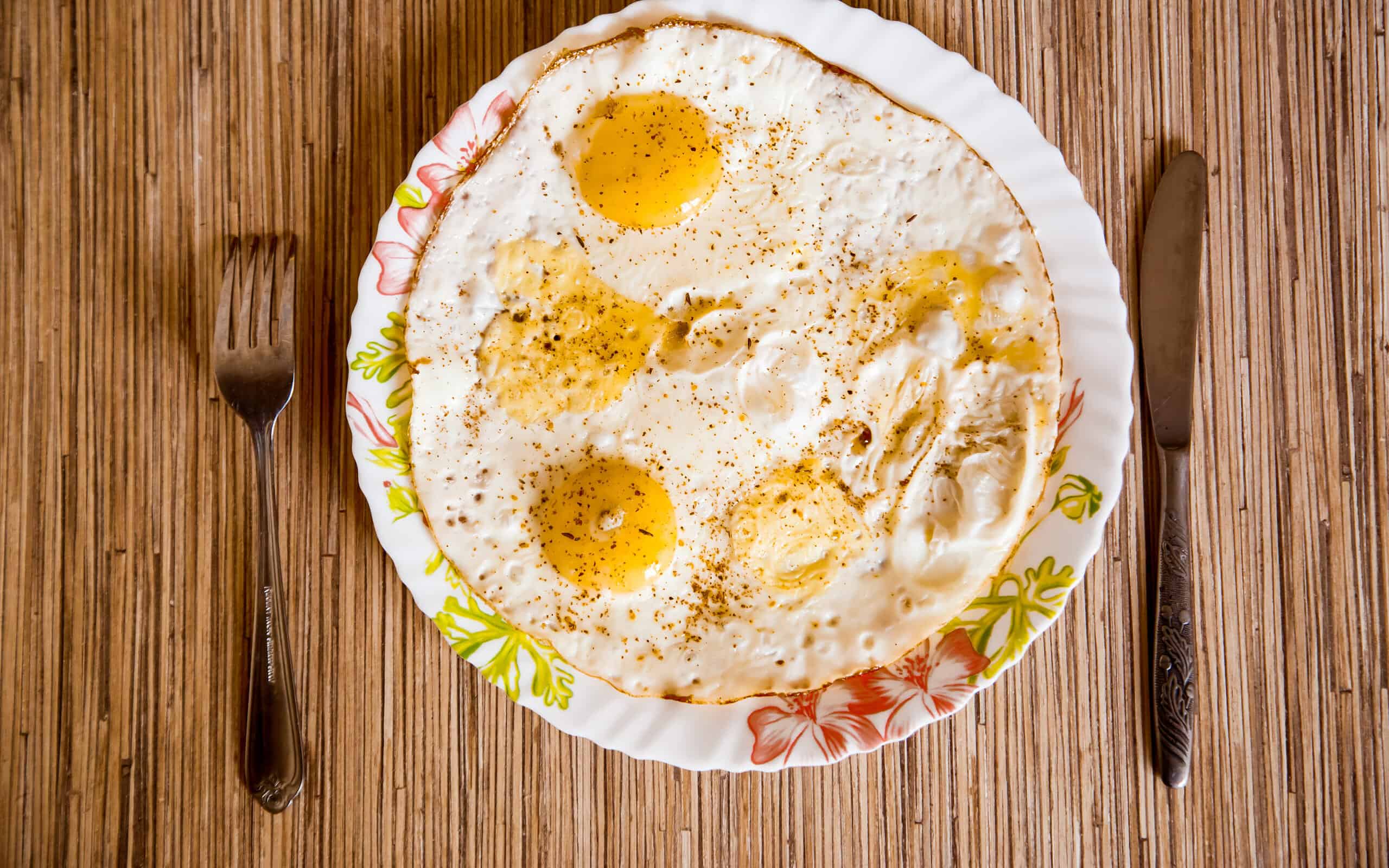 Fried eggs lie on a plate on a wooden table