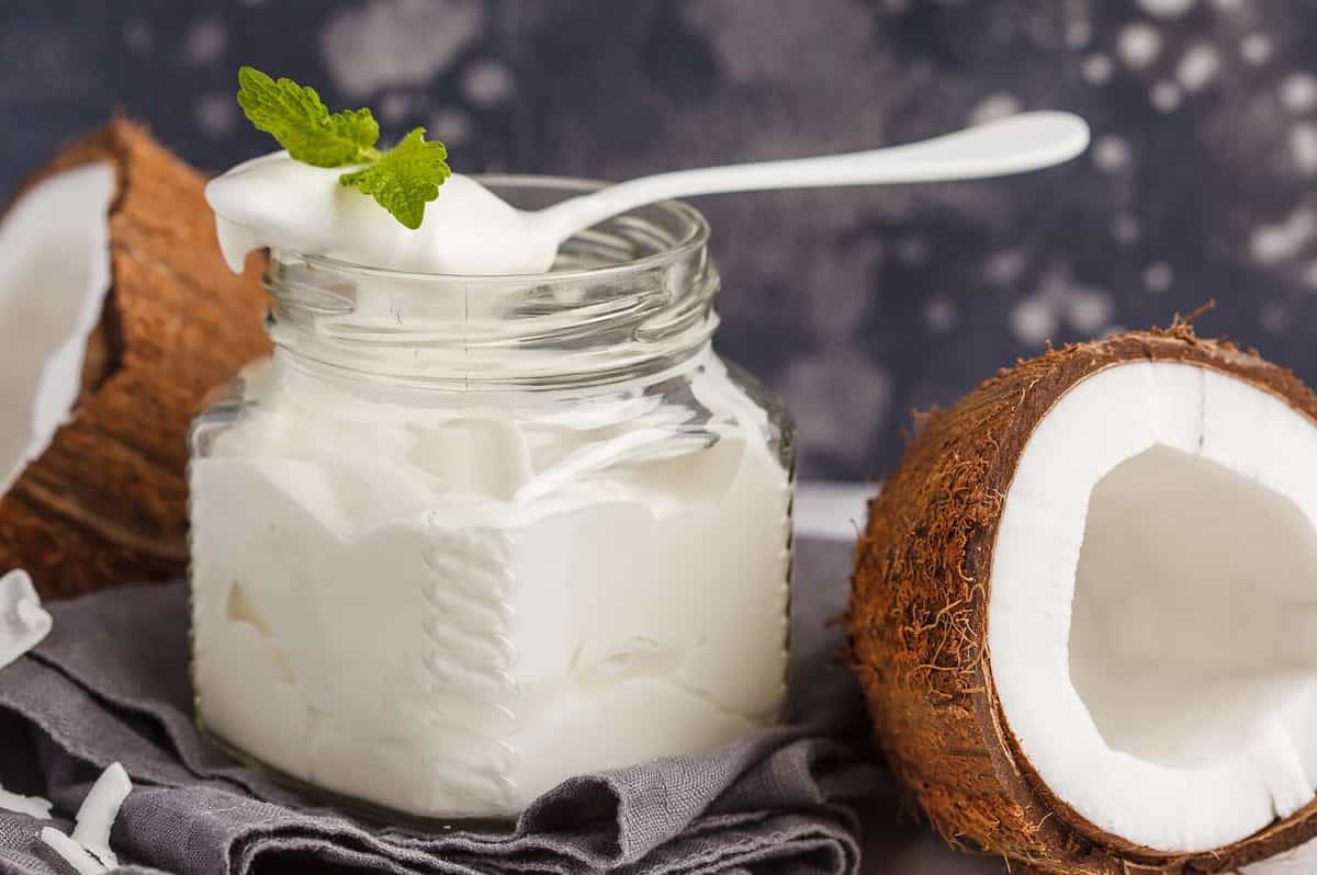 Coconut yogurt in a glass jar on a dark background, copy space. Healthy vegan food concept.