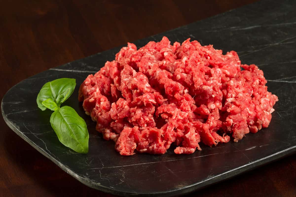 Horizontal Close Up Photo of Fresh Ground Beef with Garnish on Slate with dark table top