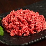 Horizontal Close Up Photo of Fresh Ground Beef with Garnish on Slate with dark table top