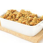 A casserole dish of herb stuffing in turkey broth on a white background