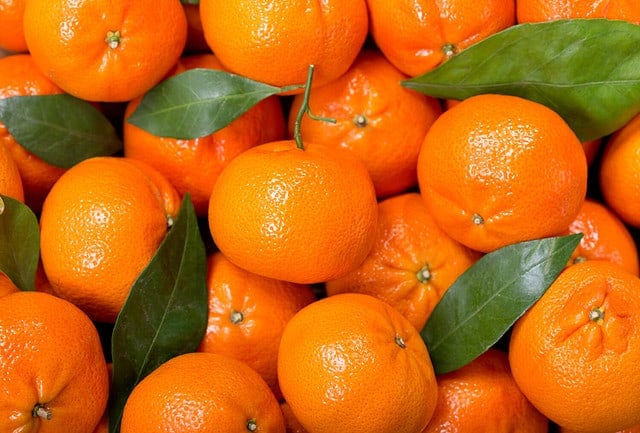 Fresh mandarin oranges fruit or tangerines with leaves, as background