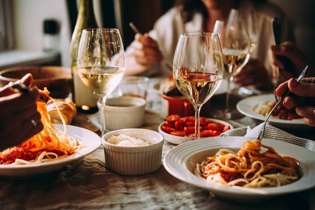 Friends having a pasta dinner at home of at a restaurant.