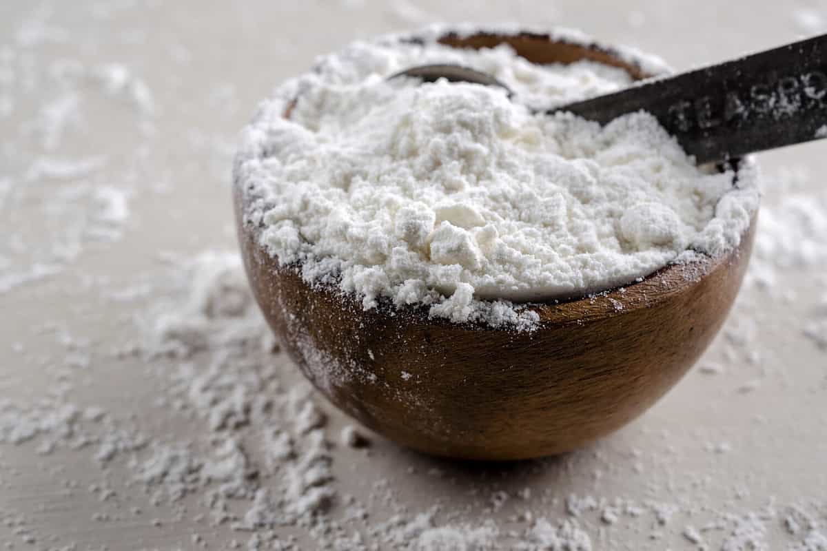 Close up photograph of a bowl of unbleached flour with a vintage metal teaspoon.