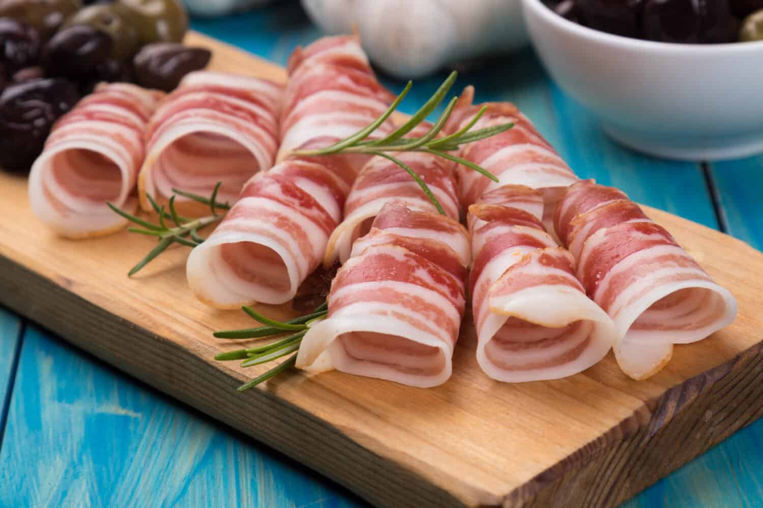 Rolls of pancetta bacon served with pickled olives, popular antipasto food