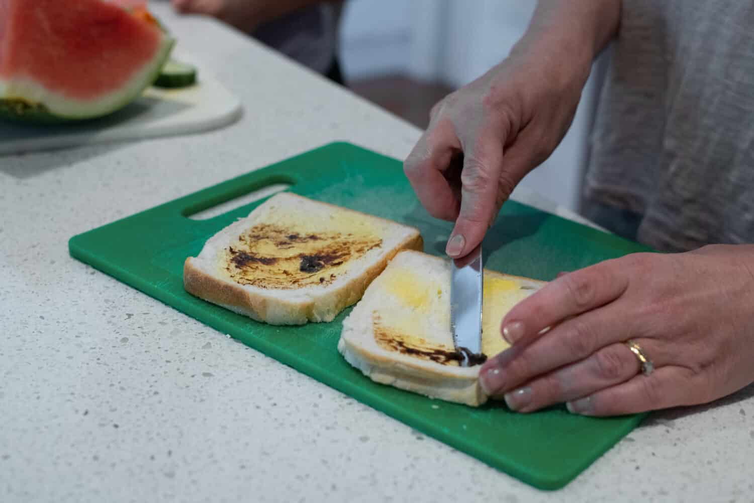 Mum making vegemite sandwich on white slice bread