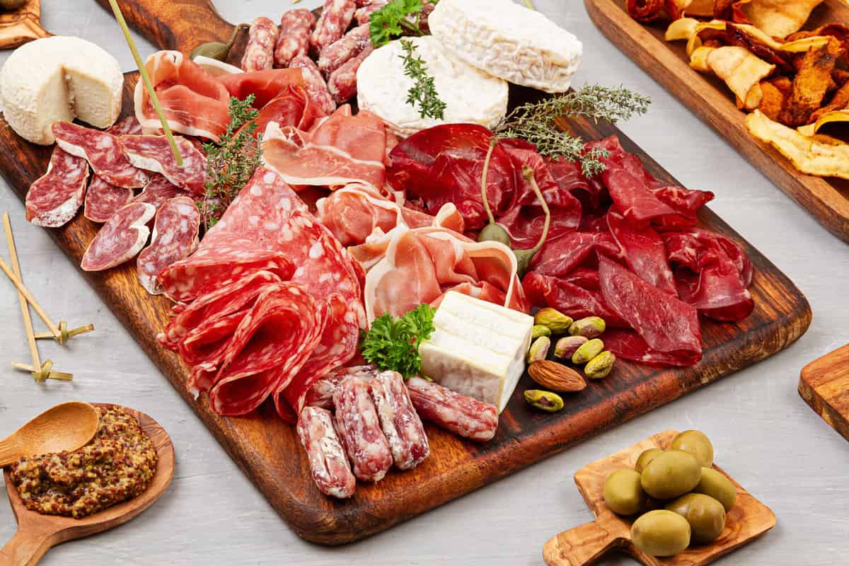 Appetizers table with differents antipasti, charcuterie, snacks and wine. Sausage, ham, tapas, olives, cheese and crackers for buffet party. Top view, flat lay