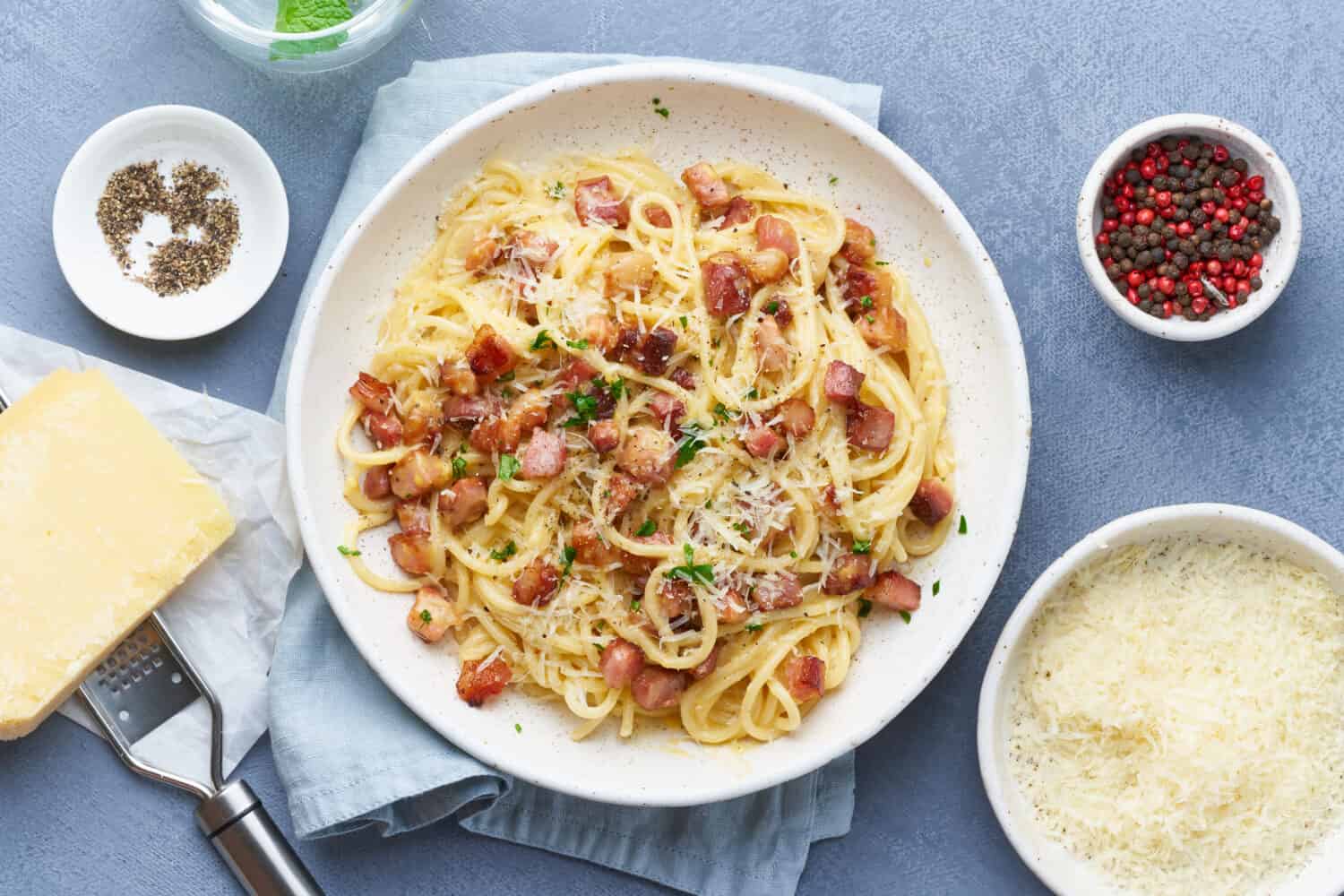 Carbonara pasta. Spaghetti with pancetta, egg, parmesan cheese, parsley and cream sauce. Traditional italian cuisine. Top view.