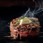 A steaming beef tenderloin steak is grilled in a grill pan with the text copy space. The concept of the recipe , filet Mignon