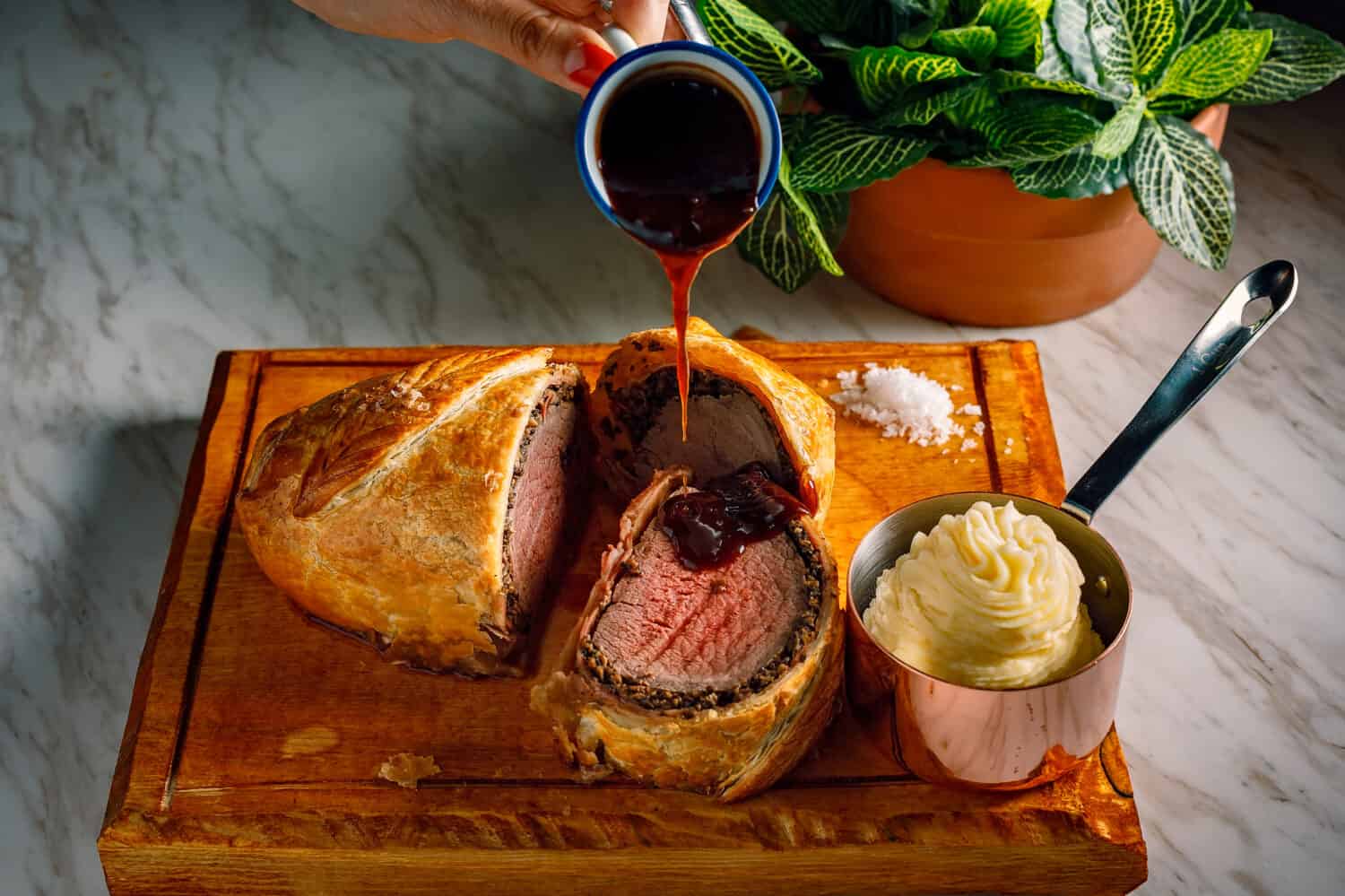Sliced Beef Wellington with the pouring sauce and the mash potatoes