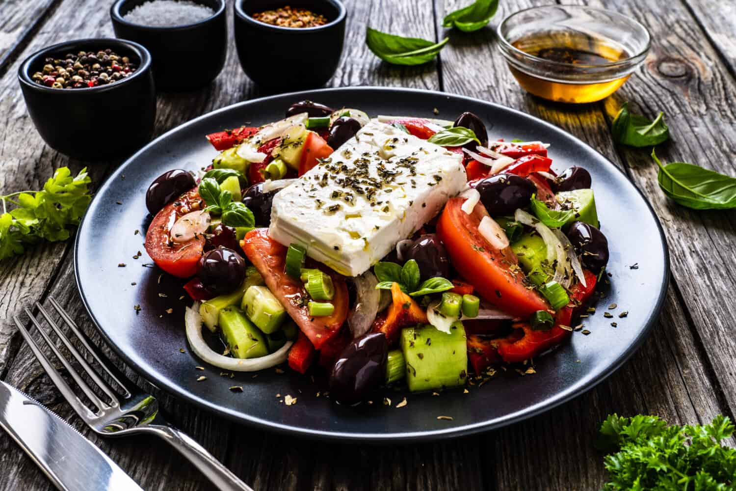 Fresh Greek salad - feta cheese, tomatoes, cucumber, red pepper, black olives and onion on wooden table