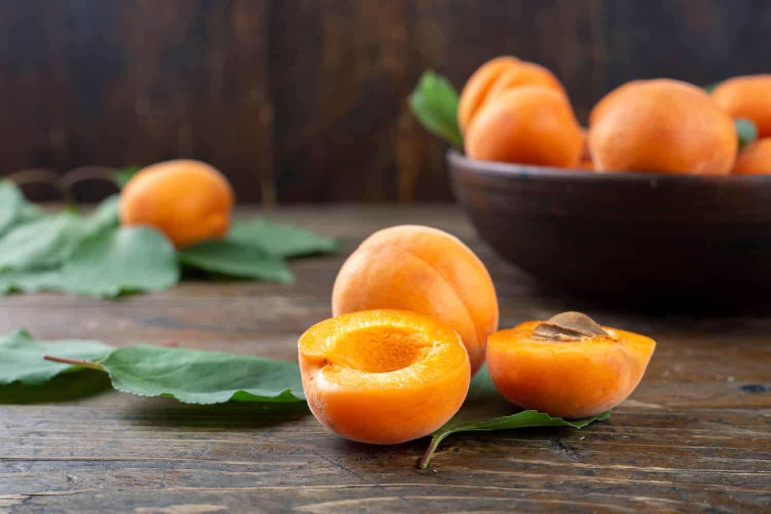 Delicious ripe apricots in a clay bowl on the table close-up. Healthy fruits.