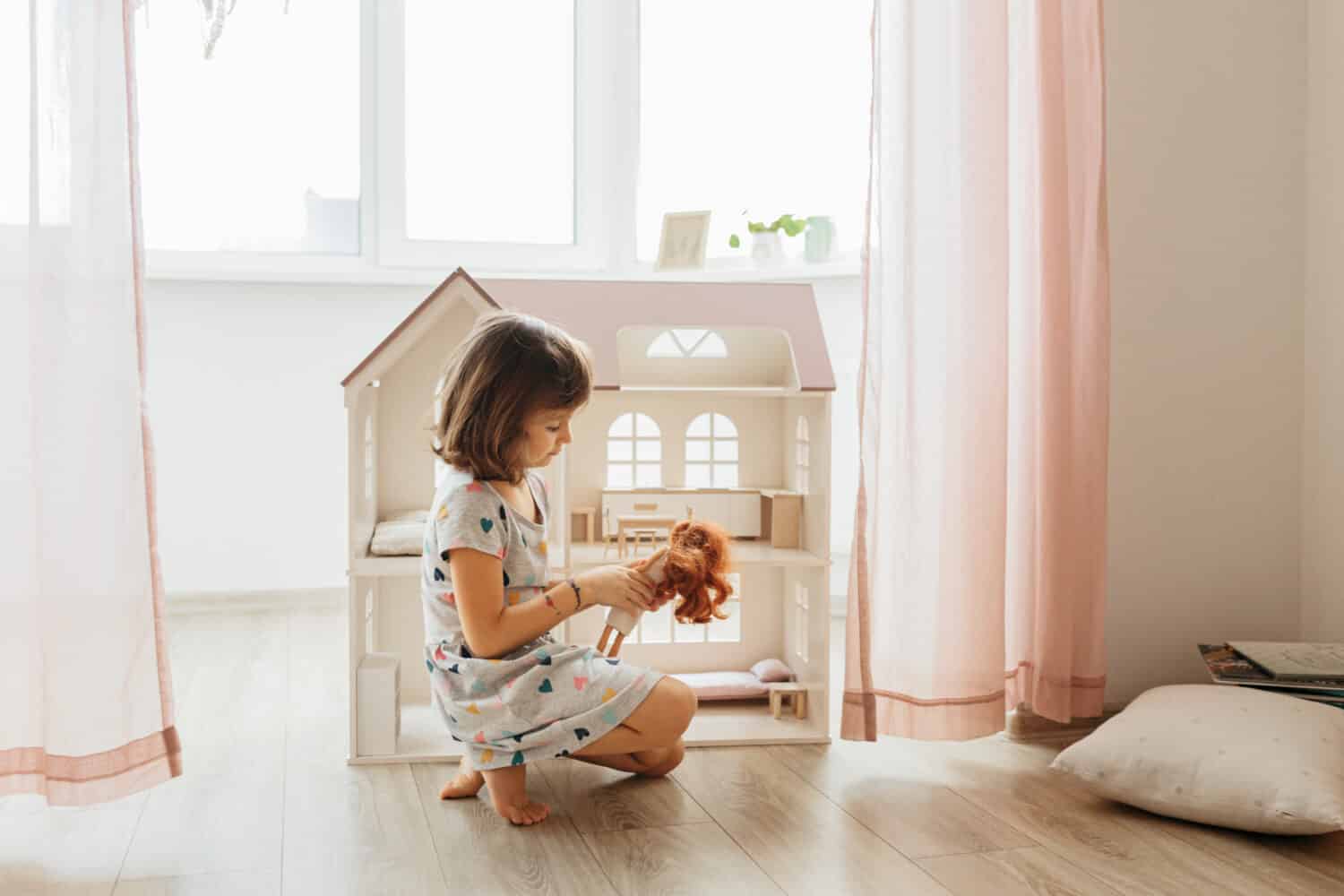 Girl playing with doll house in children room