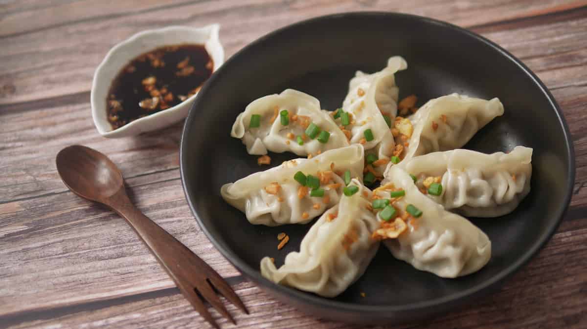 Steamed Gyoza or dumpling stuffed ground pork dipping with garlic soy sauce, famous Chinese appetiser.