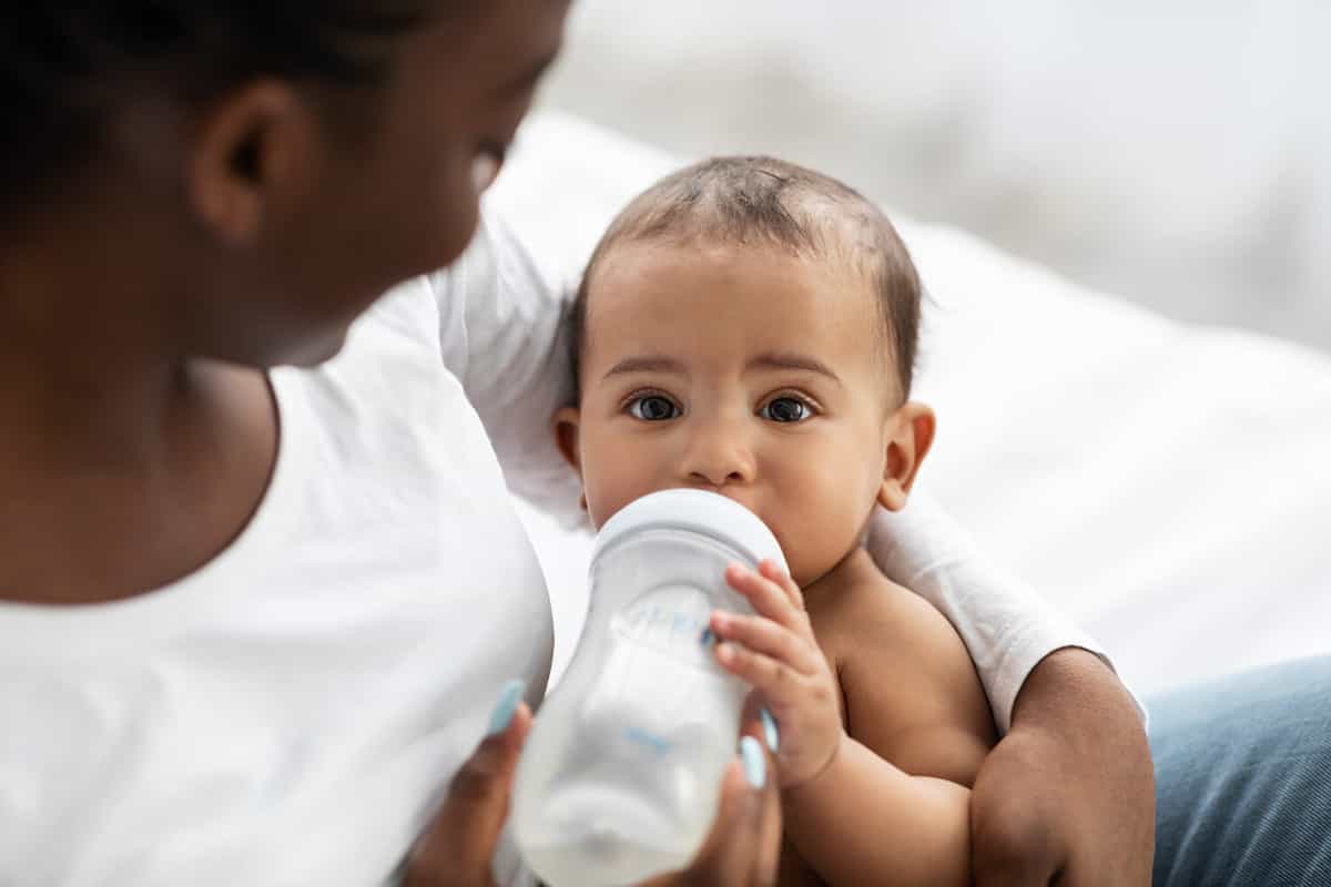 Cute little African American baby drinking from baby bottle