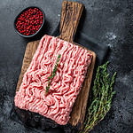 Ground chicken or turkey raw meat on wooden board. Black background. Top View. Copy space