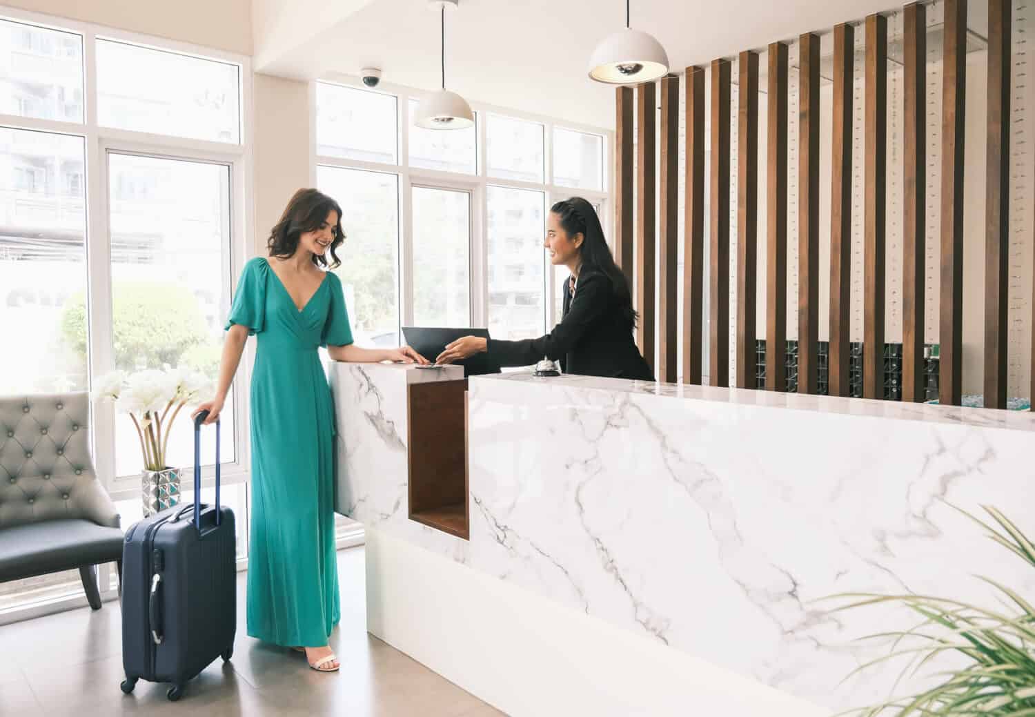 Asian girl receptionist and Caucasian woman traveler checking or checkout in hotel