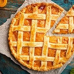 Summer apricot or peach pie homemade on blue wooden background, top view. Delicious fruit dessert. Fruit cake. Copy space.