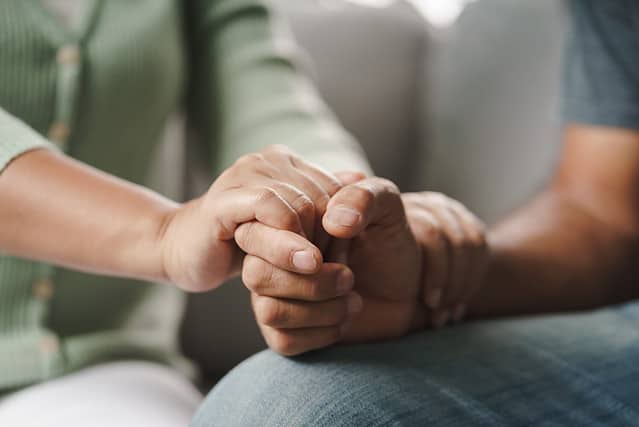 Female friend or family sitting and hold hands during cheer up to mental depress man, Psychologist provides mental aid to patient. PTSD Mental health concept