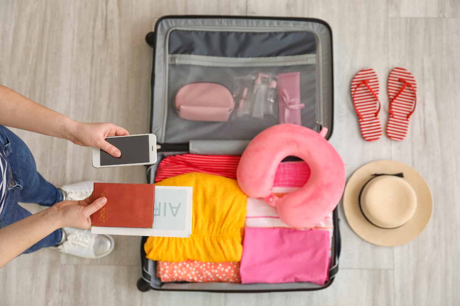 Woman packing suitcase for journey at home, top view