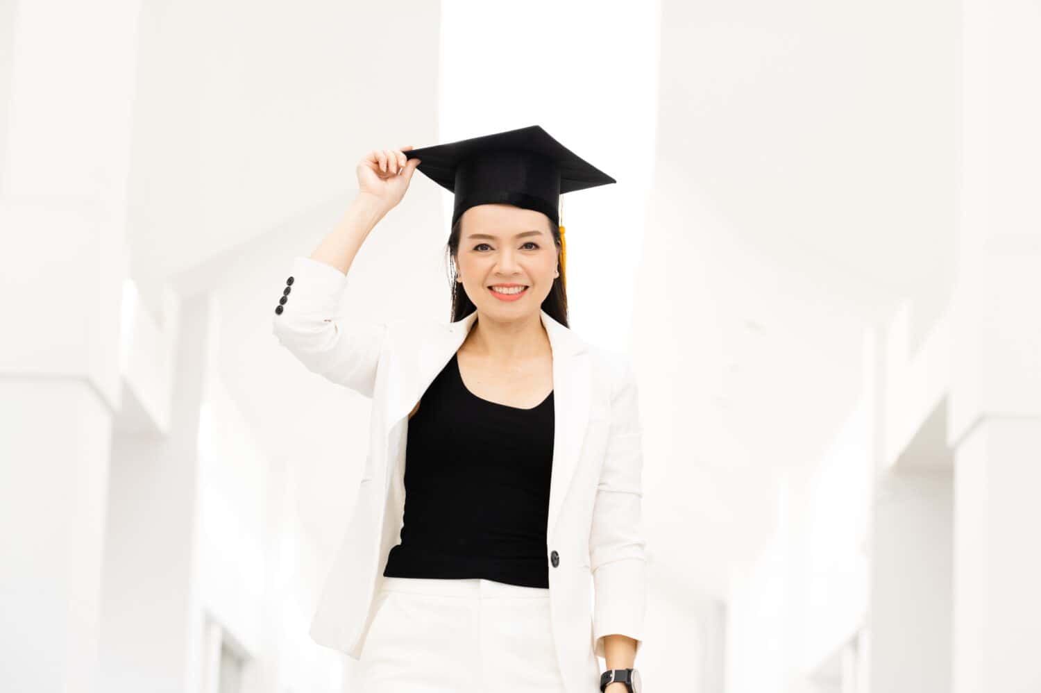 Female doctoral graduates wearing yellow tassel black graduation caps are at the university.