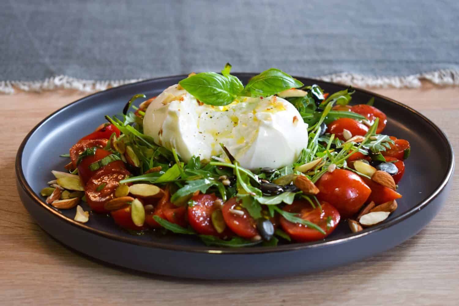 Burrata Salad with Cherry Tomatoes, Rucola, Basil, Olive Oil and Balsamic Creme. Burrata fresh cheeses tastes amazing and can be served alongside tomatoes, grilled bread, or vegetables.