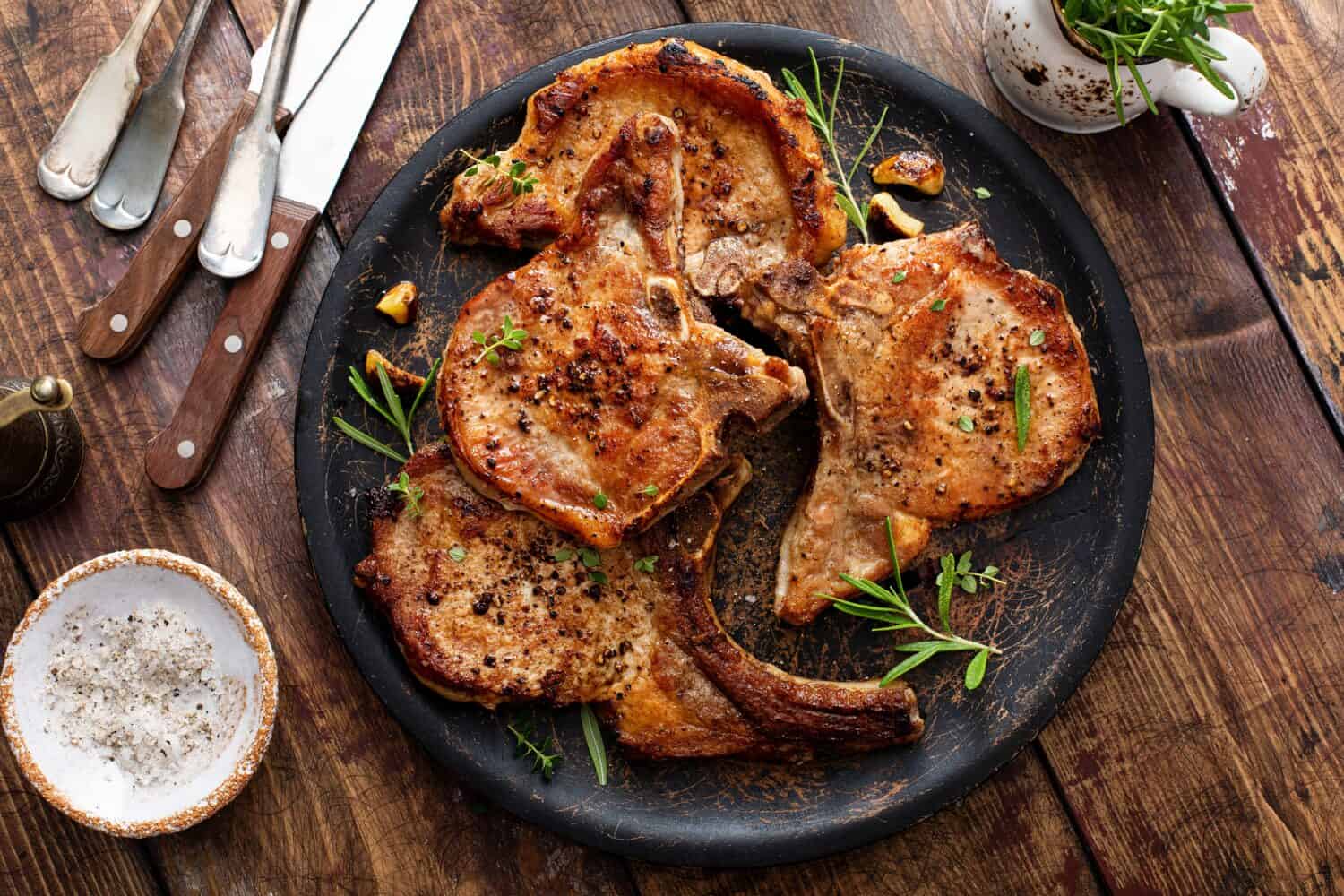 Grilled or pan fried pork chops on the bone with garlic and rosemary