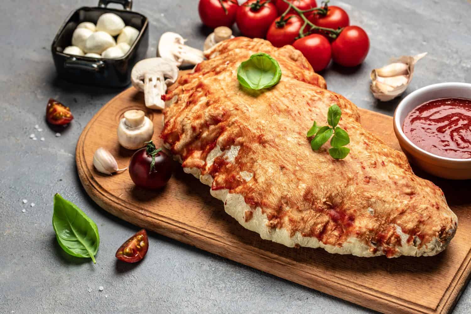 Calzone pizza with tomatoes, mozzarella, mushrooms and fresh basil, italian calzone vegetarian pizza, banner, menu, recipe place for text, top view.