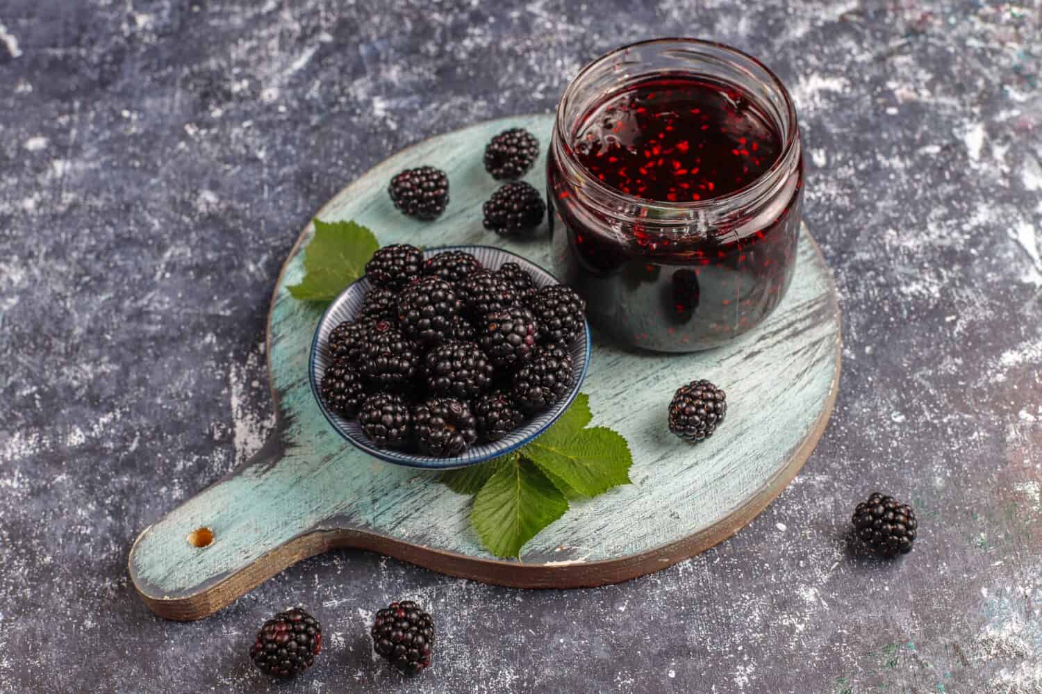 Jar of blackberry jam on marble background from top view, Fresh homemade blackberry jam in glass, Sweet homemade blackberry jam in small glass jar on wooden background, with fresh berries copy space.