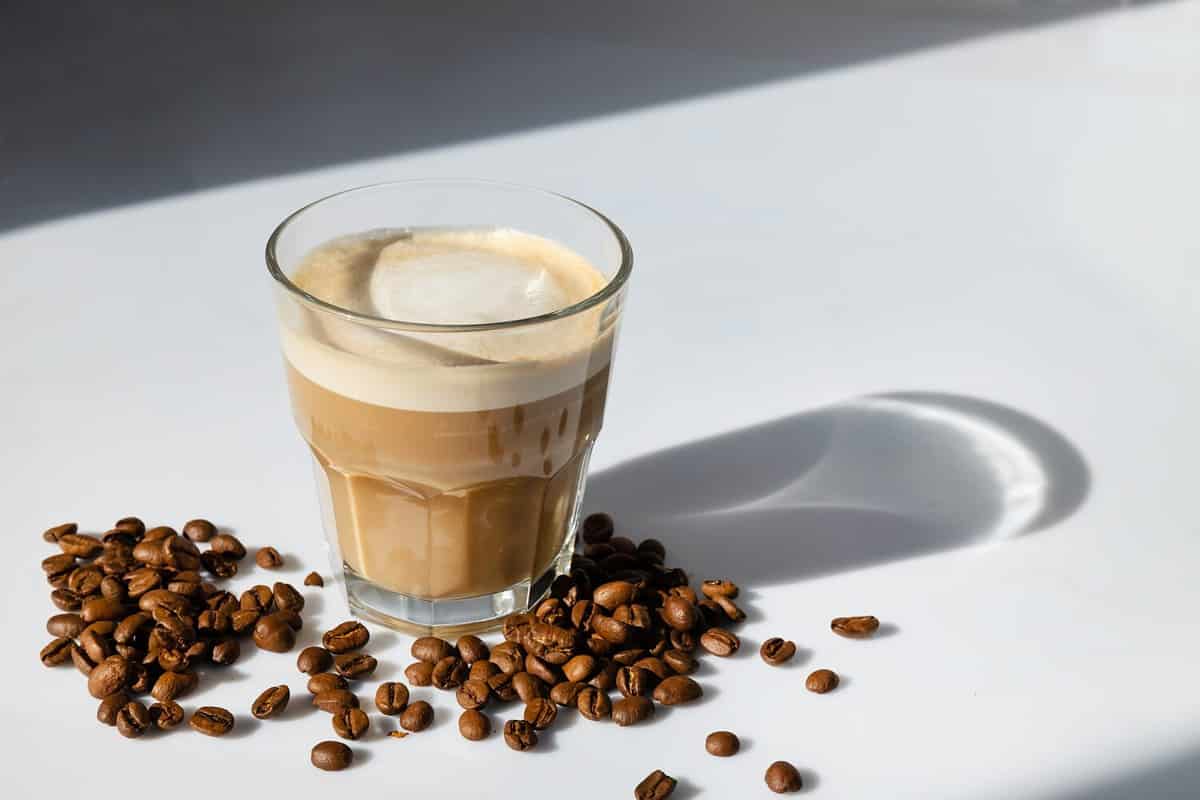 cortado coffee in a glass glass on the table with coffee beans. Spanish coffee on wall background with copy space