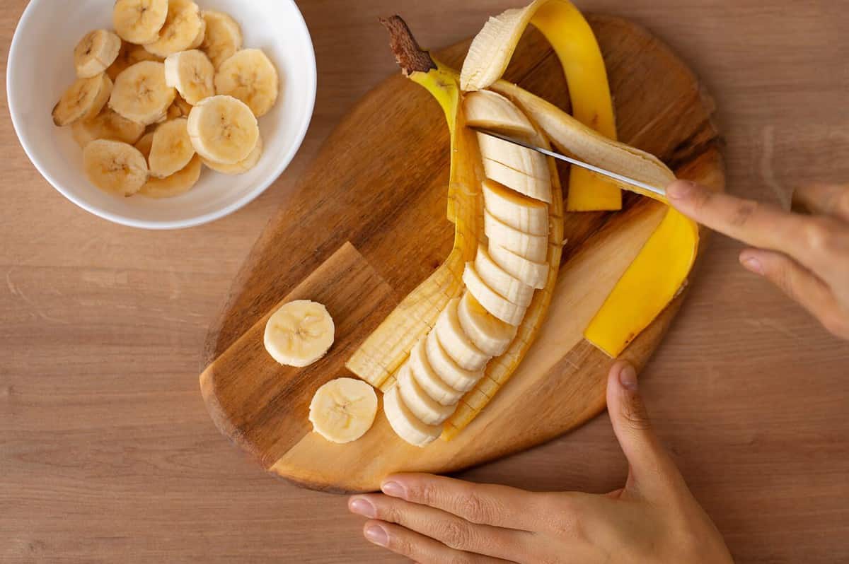 woman cutting banana slices. sliced banana. banana slices. preparing fruit salad. healthy foods.