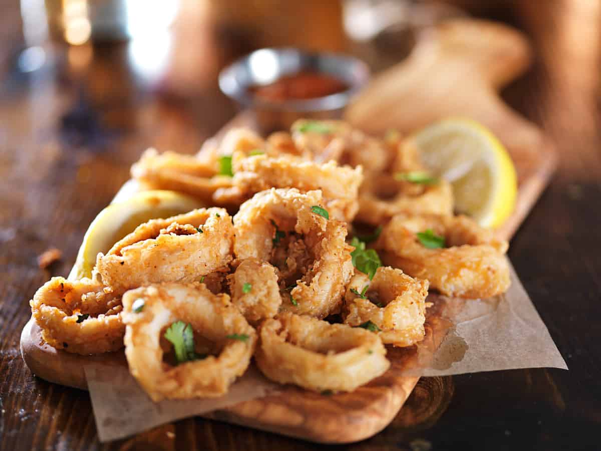 crispy calamari rings on wooden tray with lemon wedge