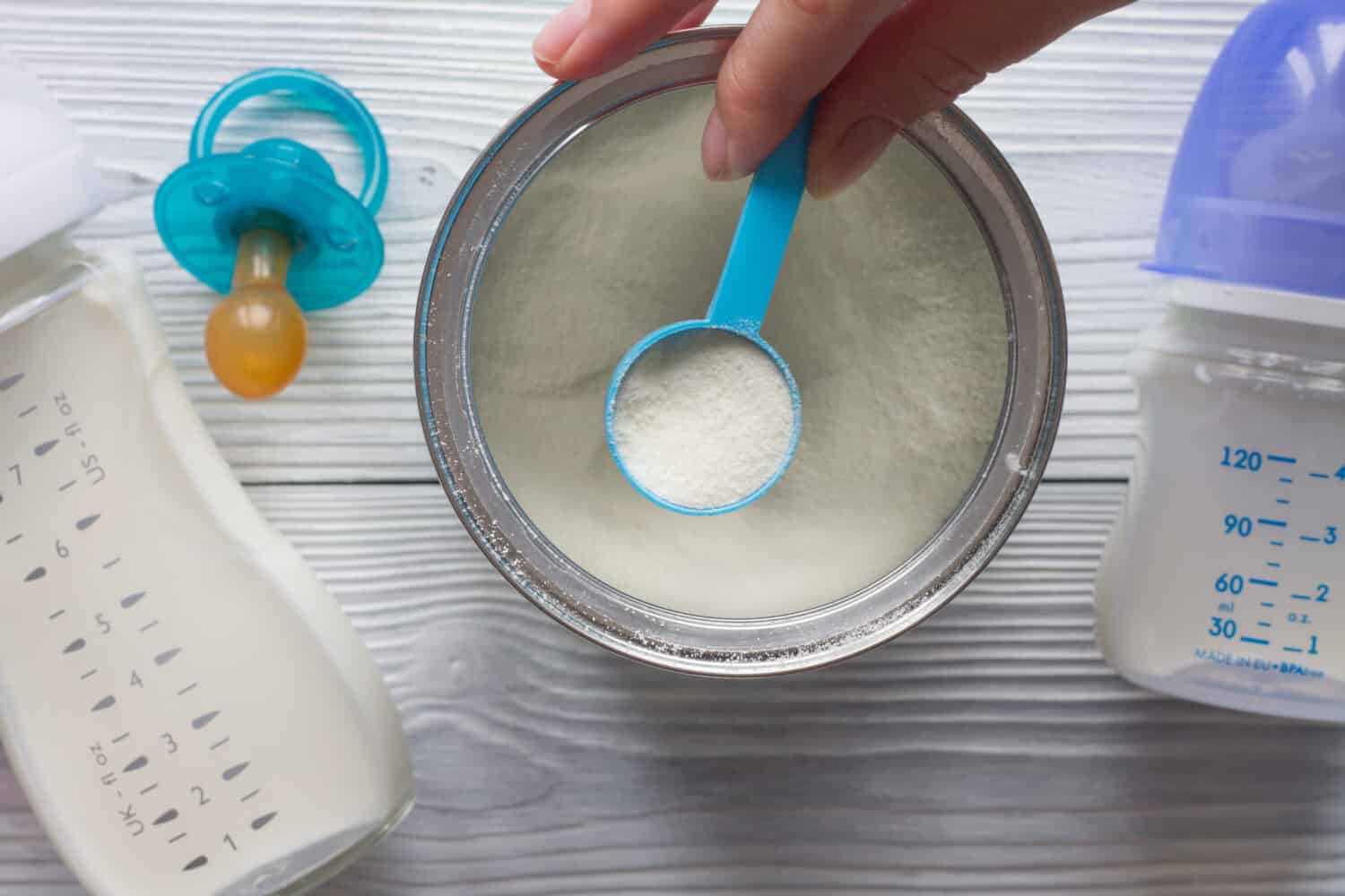 preparation of mixture baby feeding on wooden background top view