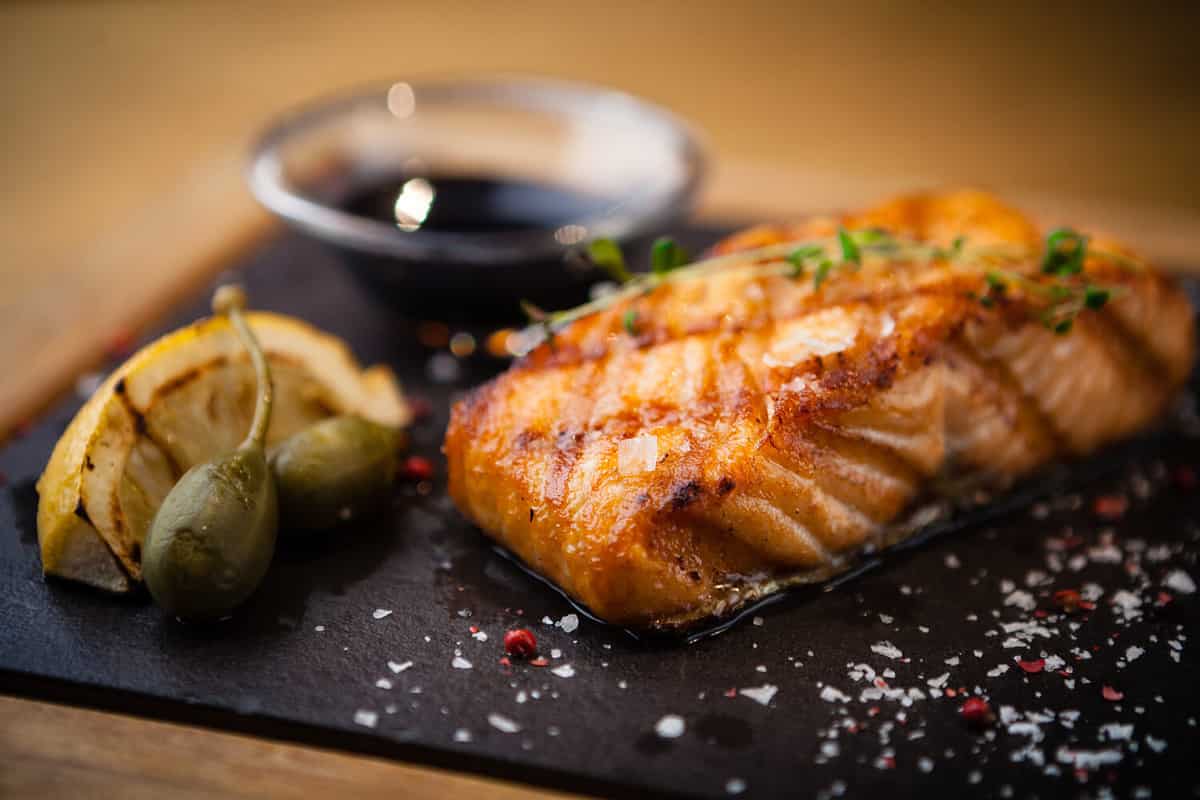 Grilled Scottish salmon with soy sauce and herb by lemon served on a stone board