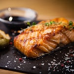 Grilled Scottish salmon with soy sauce and herb by lemon served on a stone board