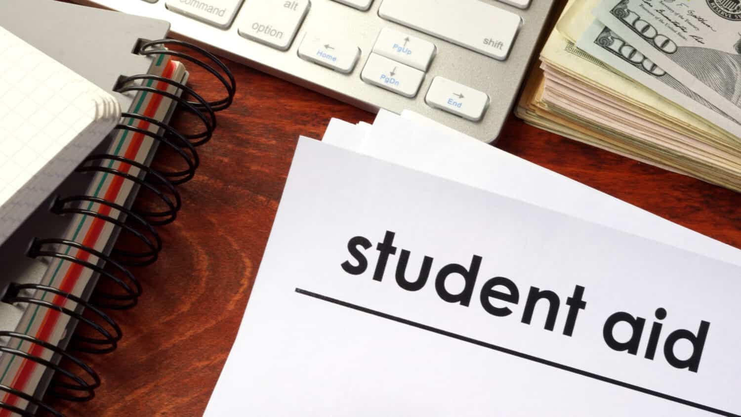 Document with title student aid and notebooks on a table.