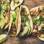 Tacos with grilled chicken, avocado, fresh salsa sauce and limes over rustic wooden background, top view. Healthy low carb and low fat lunch or food for company. Dieting and weight loss concept