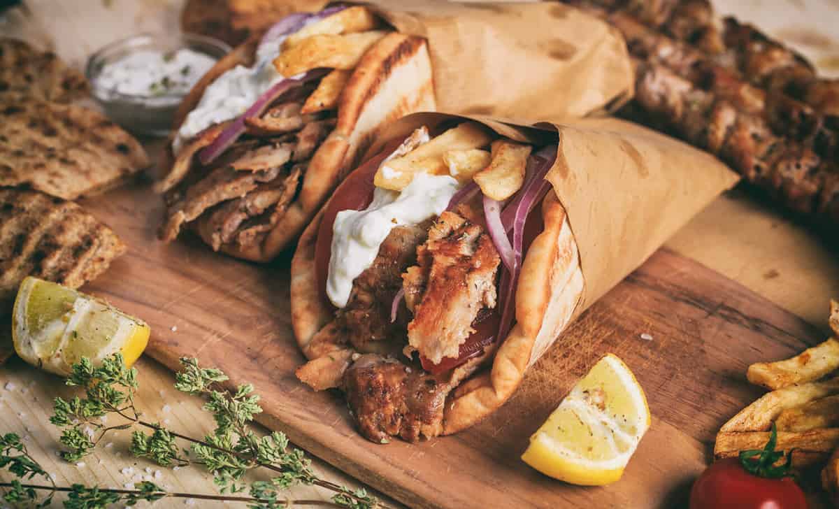 Greek gyros wrapped in pita breads on a wooden background